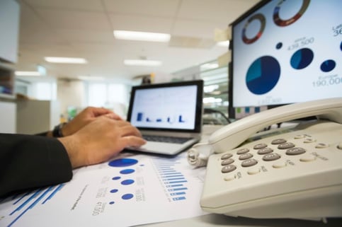 Businessman checking reported profits on the paper and laptop.